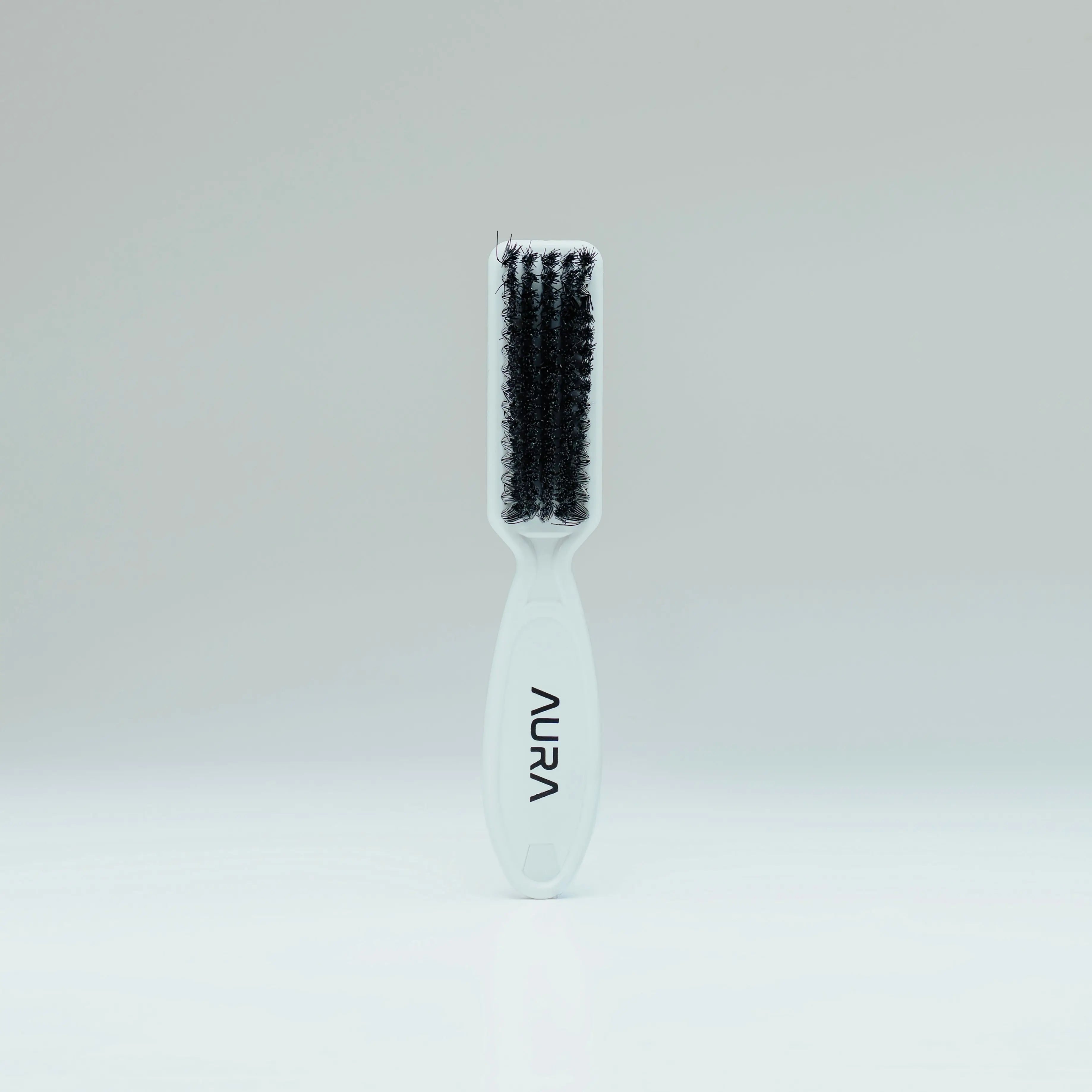 White aura hairbrush for fade with black bristles on a light gray background